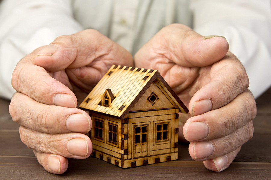 hands protecting a model of a house